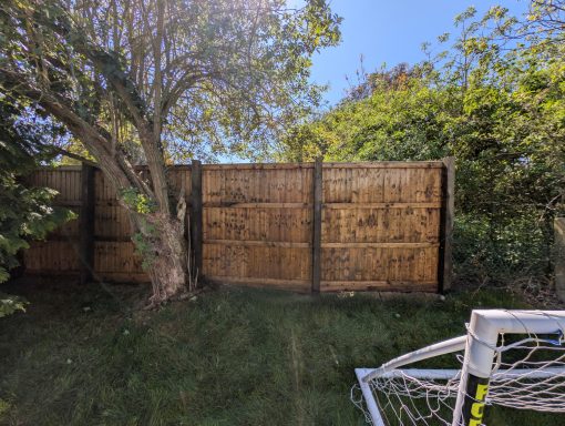 Timber fence after pressure washing and removal of accumulated dirt and organic growth in Onehouse, Suffolk